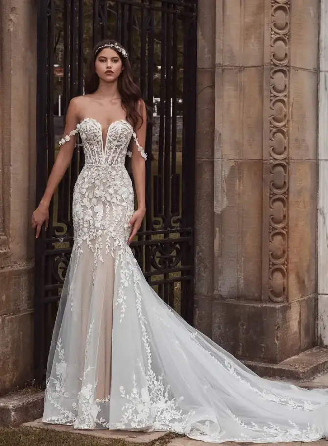 model is wearing an off the shoulder lace trumpet wedding dress