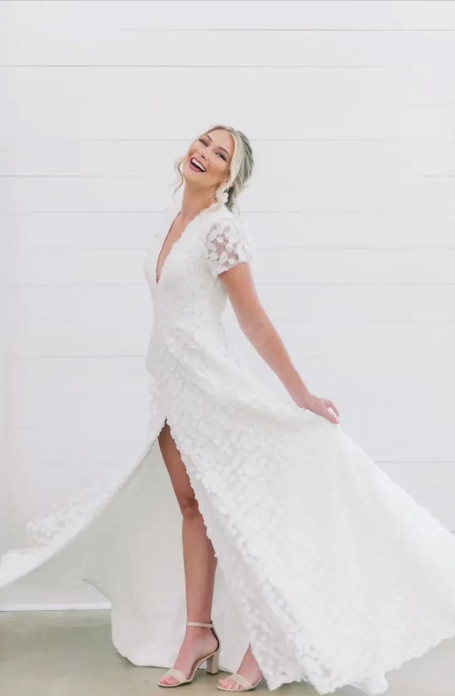 model is wearing an a-line wedding dress with lace details, short sleeves, v-neckline