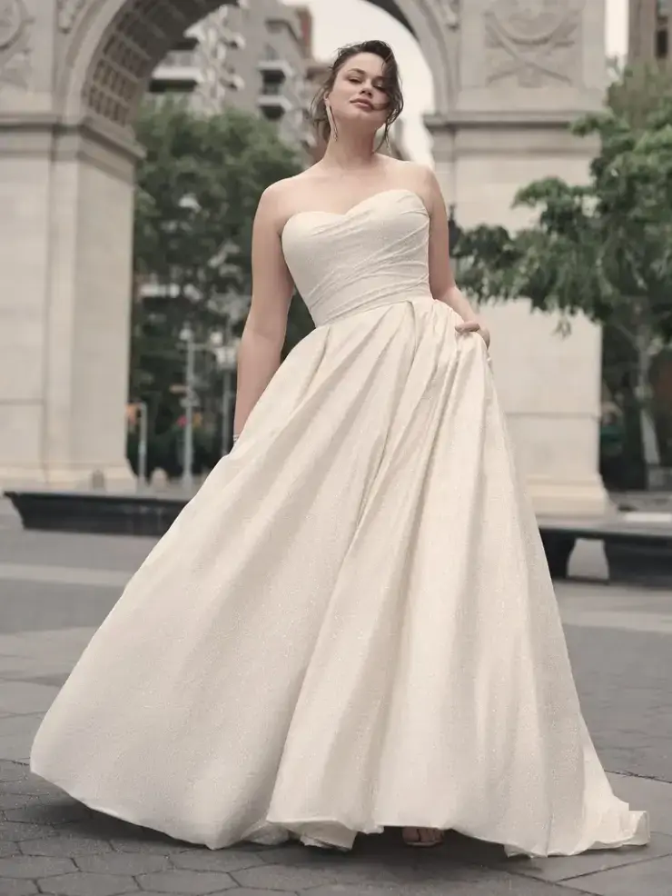 model is wearing a plus size strapless ball gown wedding dress