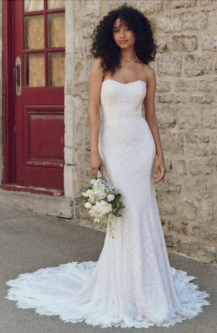 model is wearing a strapless fit and flare lace bridal gown