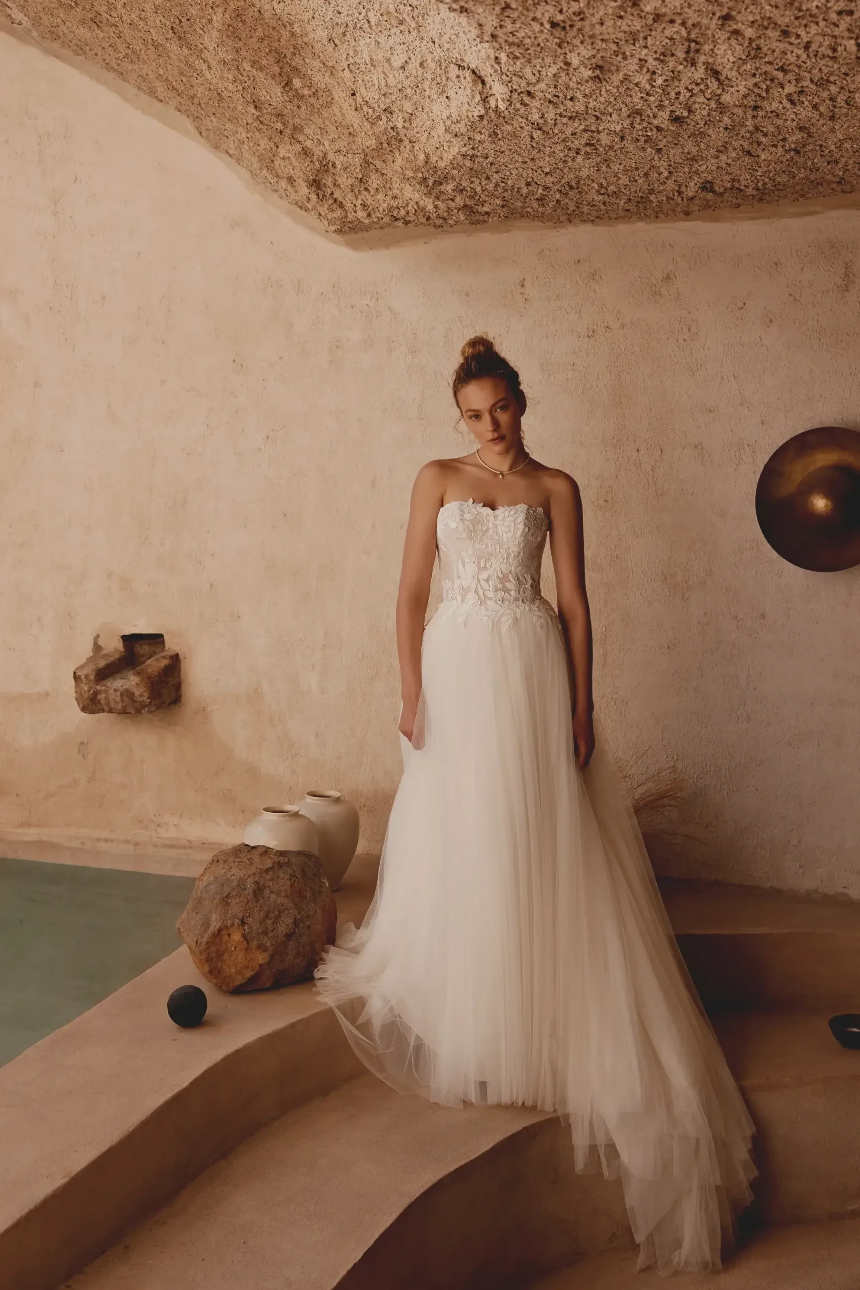 model is wearing a strapless a-line wedding dress with a tulle skirt