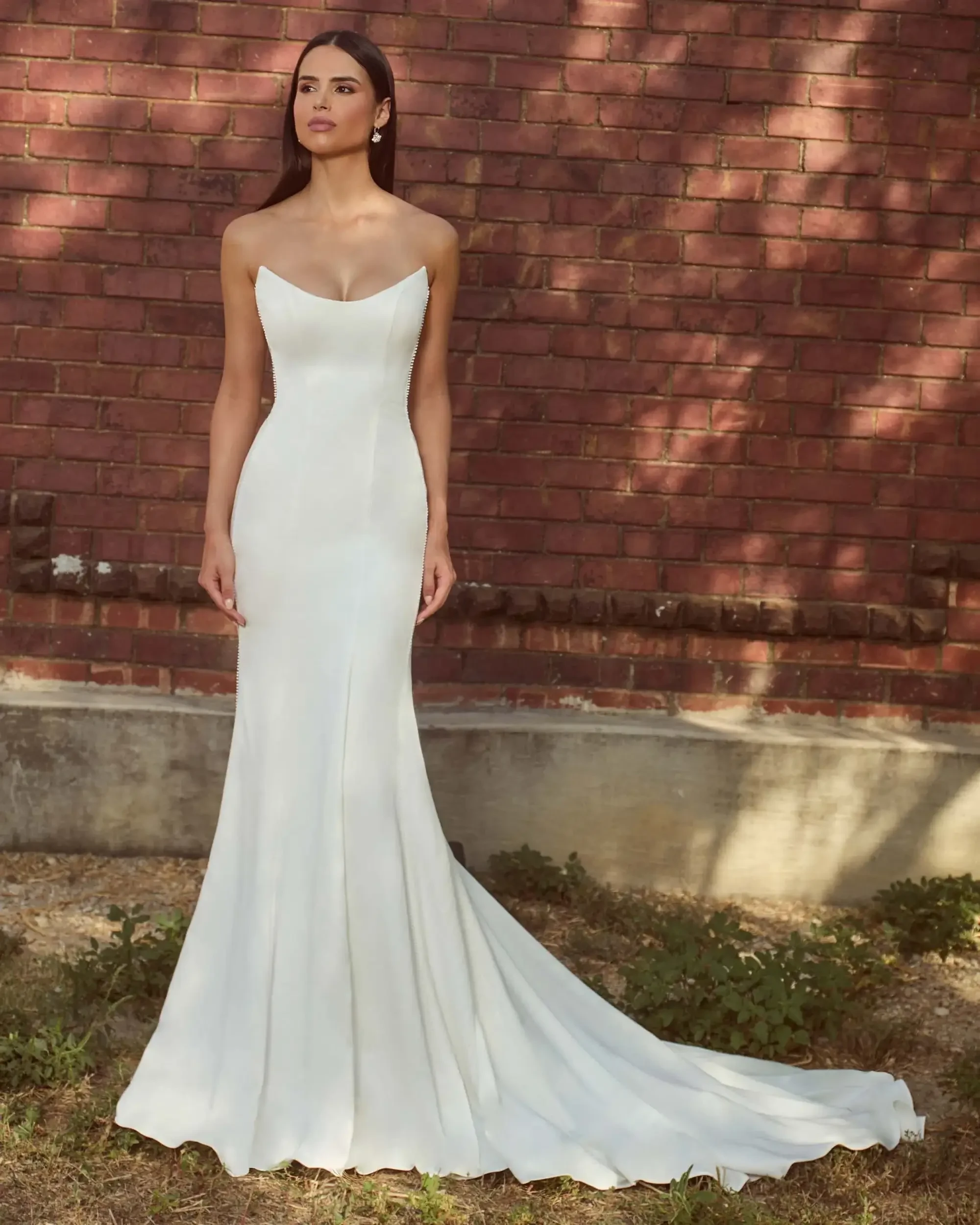 model is wearing a sleeveless minimalist fit and flare wedding dress