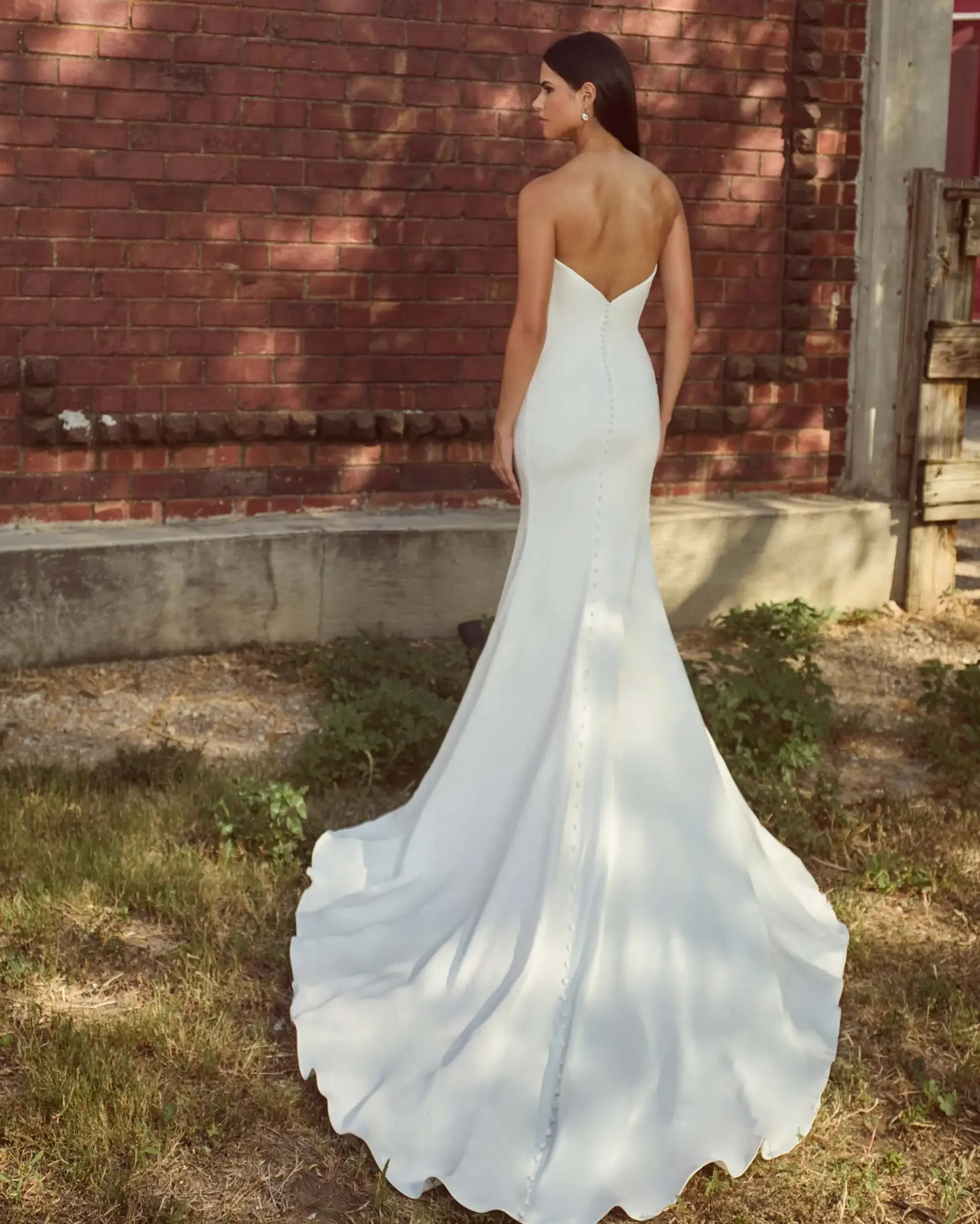 model is wearing a sleeveless minimalist fit and flare wedding dress